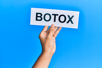 Hand of caucasian man holding paper with botox word over isolated blue background