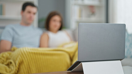 Beautiful couple watching movie on laptop sitting on sofa at home