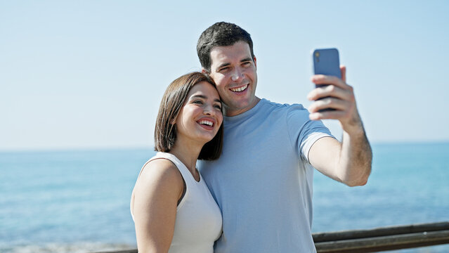 Beautiful couple smiling confident make selfie by smartphone at seaside