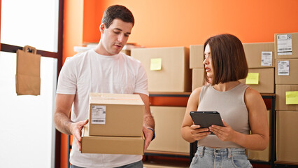 Two workers man and woman using touchpad checking packages at office