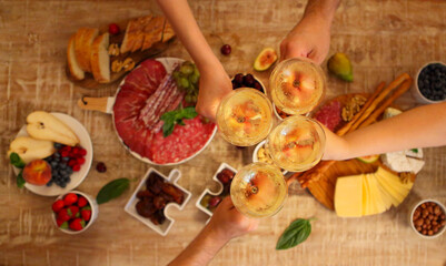 Hands of a group of people cheering with white wine