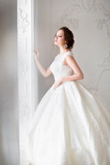 Beautiful brunette woman with bouquet posing in a wedding dress