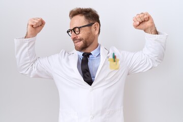 Middle age doctor man with beard wearing white coat showing arms muscles smiling proud. fitness concept.