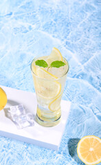 fresh lemon water in glass with lemon slices fruits on sea beach with. Summer sea vacation and travel concept. Exotic summer drinks.