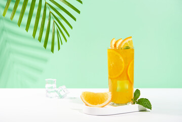 Glass of 100% Orange juice with orange slices fruits on pastel color background. Summer sea vacation and travel concept. Exotic summer drinks.