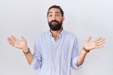 Hispanic man with beard wearing casual shirt clueless and confused expression with arms and hands...