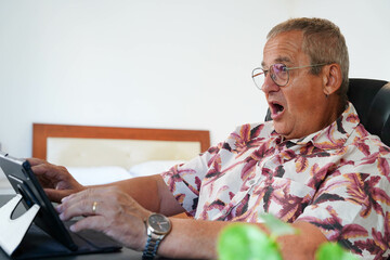 Surprised man looking at a digital tablet sitting at home