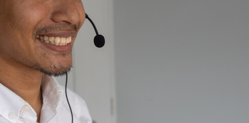 close up young call center indian man wear headset and smiling while working in office with...