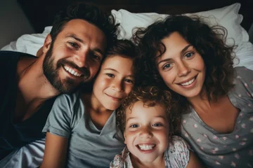 Fotobehang Portrait of a happy family smiling in bed © Baba Images
