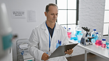 Middle age man, a dedicated scientist, engrossed in reading medical report with a serious expression at his research lab