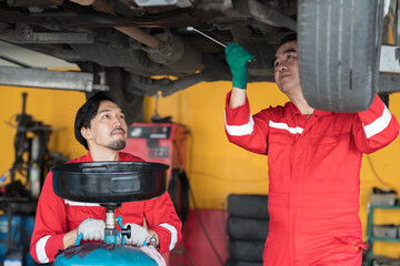Group of male mechanic repair, fix car engine underneath lifted of car in auto repair shop. Team of...
