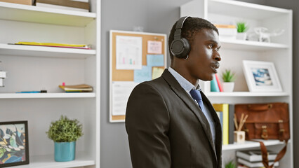 African american man wearing headset in modern office setting listening attentively during a...