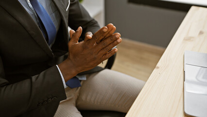 African american man in a suit gestures with his hands at an office setting, showing...