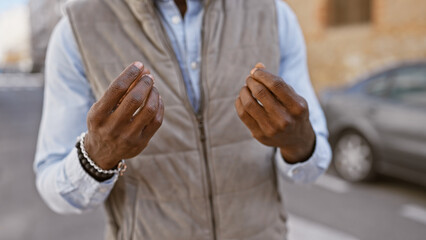 Obraz premium African american man in a vest gesturing outdoors in an urban street setting.