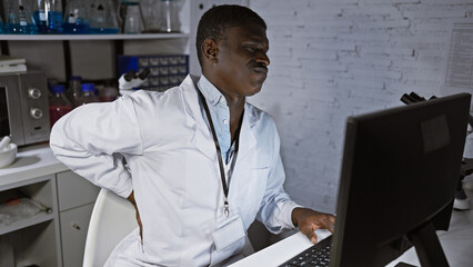 African man in lab coat expresses discomfort at workplace in laboratory