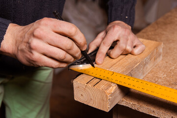 A carpenter works in a furniture workshop with various tools and a board