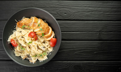 Farfalle pasta in cream sauce with chicken and tomatoes. Chicken italian bow tie pasta. Homemade italian food concept.