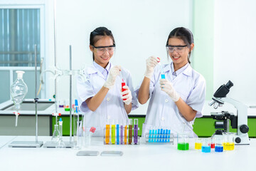 2 Asian female scientists are doctors Drops of solution in vaccine production test tube with...