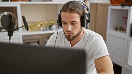 Young hispanic man musician listening to music at music studio