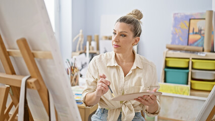 Young blonde woman artist drawing with serious face at art studio