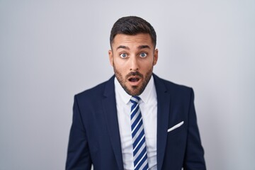 Handsome hispanic man wearing suit and tie afraid and shocked with surprise and amazed expression,...