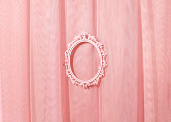 Light pastel pink tulle curtain, oval picture frame in the middle, creative copy space, place for...