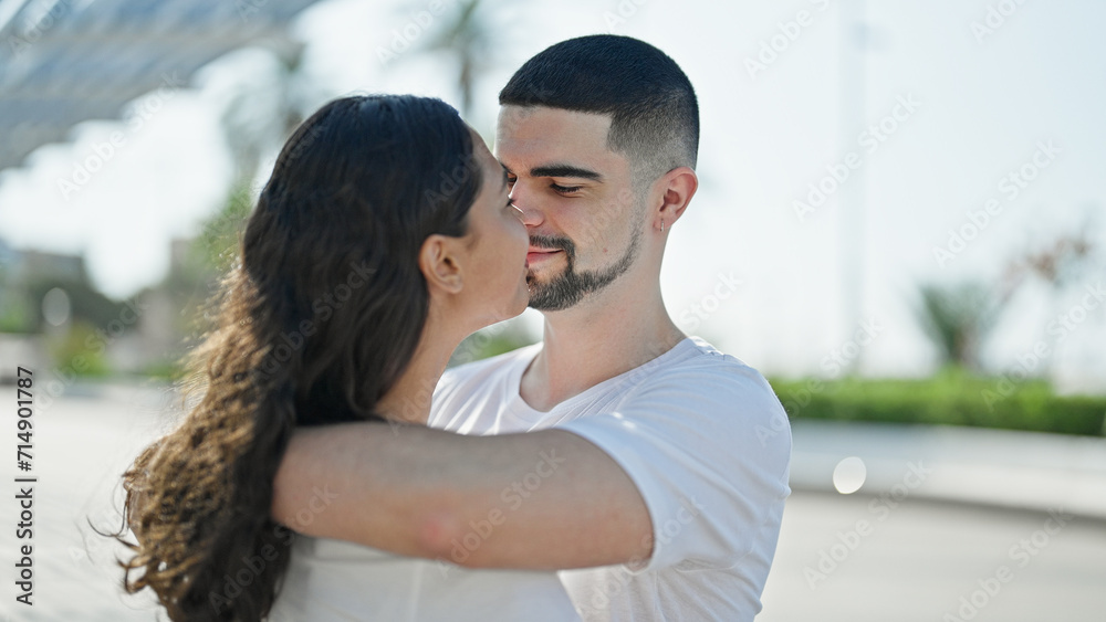 Wall mural Beautiful, confident couple, smiling and hugging, deeply looking into each other's eyes expressing positive joy, basking in sunlight at the city park. lifestyle of love and happiness outdoors.