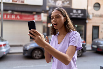 Young african american woman using smartphone with surprise expression at street