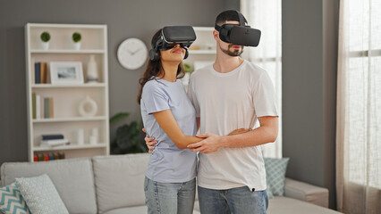 Gorgeous couple sharing love, gaming together with vr glasses at home, exploring futuristic cyber...