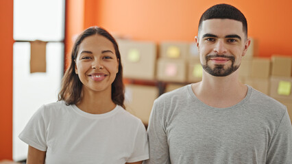 Two smiling workers, a man and woman standing together, brimming with confidence at their office,...