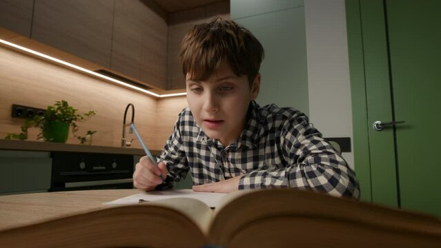 Kid with Autism concentrates on writing while immersed in a book. Embracing the unique approach to education and dedication.