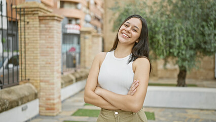 Young beautiful hispanic woman smiling confident standing with arms crossed gesture at park