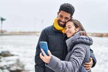 Man and woman couple smiling confident using smartphone at seaside - obrazy, fototapety, plakaty