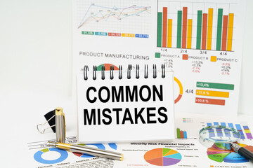 On the table are reports with graphs and a notepad with the inscription - Common Mistakes