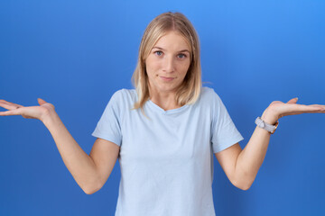 Young caucasian woman wearing casual blue t shirt clueless and confused expression with arms and...