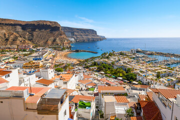 Fototapeta na wymiar Scenic panoramic view from the lookout viewpoint of the bay, beach, harbor, mountains and village of Puerto de Mogan, Spain, Canary Islands.