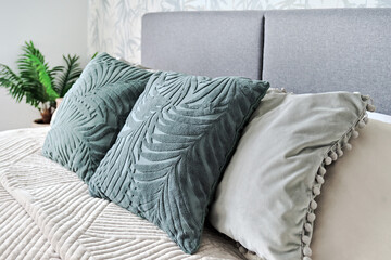 Close up of three green cushions on bed in cozy bedroom