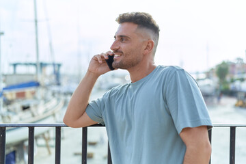 Young hispanic man smiling confident talking on the smartphone at seaside