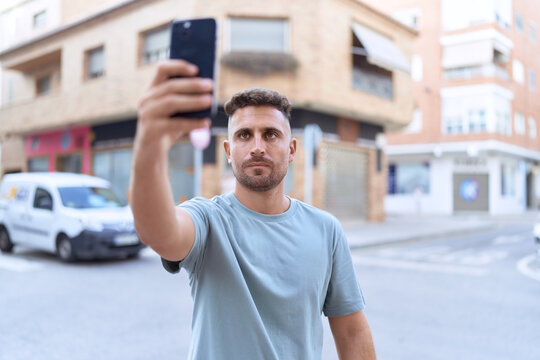 Young hispanic man making selfie by the smartphone at street