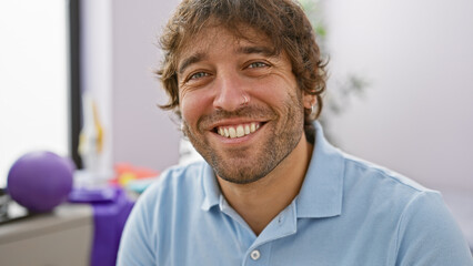 Portrait of a cheerful young man with a beard in a clinic, conveying a sense of wellbeing and...