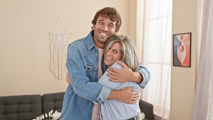 Confident mother and son share a warm, smiling hug indoors, enjoying their love-filled, casual lifestyle in their happy home.