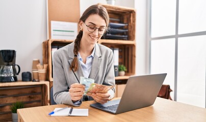 Young caucasian woman business worker using laptop counting canada dollars at office