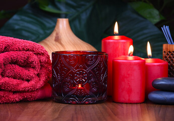 Obraz na płótnie Canvas Spa still life with red candles, towel and massage stones on wooden background stock photo images. Spa wellness setting with red burning candles, towel and pebbles. Beauty spa treatment composition