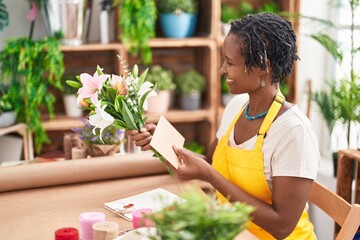 Middle age african american woman florist make selfie by smartphone holding lavender plant at flower shop - Powered by Adobe