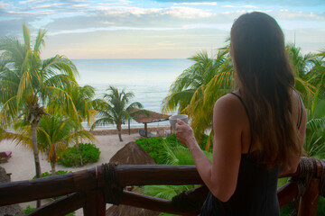 Female enjoying the sunrise and coffee from a balcony in Holbox Mexico