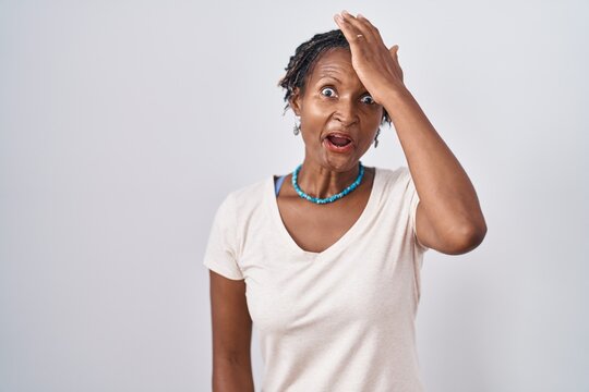 African woman with dreadlocks standing over white background surprised with hand on head for mistake, remember error. forgot, bad memory concept.