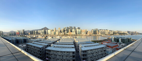 Obraz premium Maginificent View from Kai Tak Cruise Ferry Terminal Park, rooftop level, seeing the promenade, harbour, strait, and Hong Kong skyscrapers at a distance.