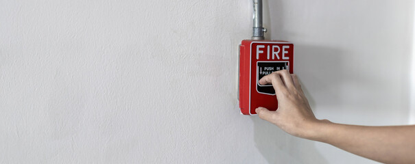 Woamn or worker pushing fire alarm on the wall. A fire! or Emergency case at the factory building. Emergency of Fire alarm or alert or bell warning equipment. - obrazy, fototapety, plakaty