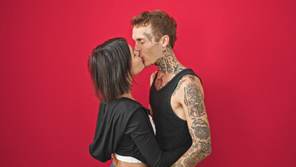 Beautiful couple hugging each other kissing over isolated red background