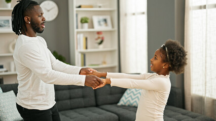 African american father and daughter smiling confident dancing at home